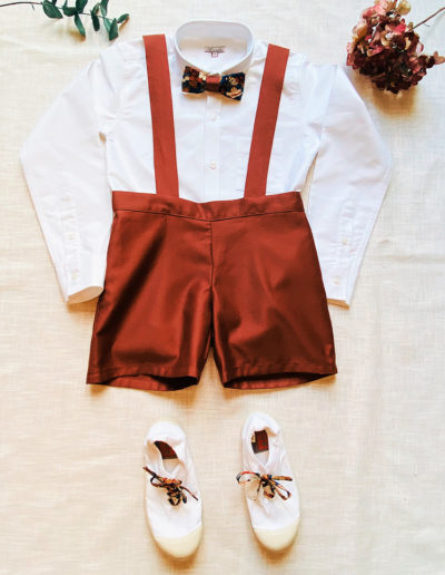 Look d'enfant d'honneur : chemise blanche oxford, nœud papillon en Liberty, Bermuda l'Imperturbable avec bretelles en satin de coton terracotta, bensimon blanches avec lacets en Liberty