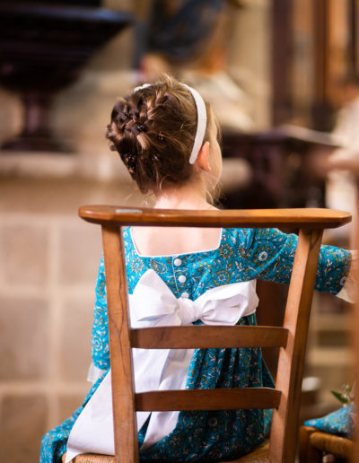 Petite fille d'honneur de dos durant une messe de mariage